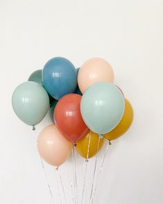 a bunch of balloons floating in the air on a white wall with some string attached to them