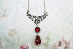 Silver Art Nouveau Necklace- Dark Academia Necklace- Vintage Inspired 1920's Necklace- Red Glass Teardrop Necklace- Ren Faire- Great Gatsby Hanging from a silver plated centerpiece  Is a red square glass framed stone with a  Red faceted teardrop  with a silver bead cap The necklace is 16 inches with a 3 inch extension chain  that has a red Swarovski bicone crystal   The chain is a dainty  antiqued silver link chain The centerpiece is 1 1/2 inches wide and the drop is 2 1/2 inches from the top of the centerpiece.  The red drop is 1 1/4"  It arrives in a gift box with a bow Classic Red Teardrop Pendant Necklace, Vintage Red Teardrop Jewelry, Classic Red Teardrop Necklace, Vintage Dangle Drop Necklace For Gift, Red Drop Necklaces For Formal Occasions, Red Victorian Necklace For Anniversary, Red Handmade Victorian Necklace, Handmade Red Victorian Necklace, Handmade Victorian Red Necklace