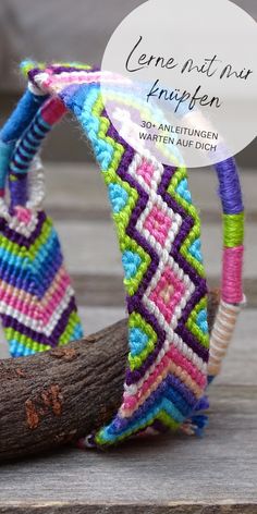 two colorful bracelets sitting on top of a piece of wood