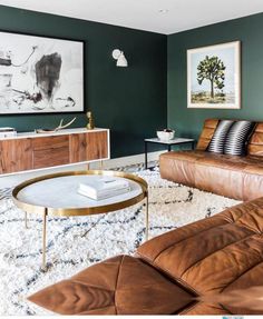 a living room with green walls and brown leather couches in front of a coffee table