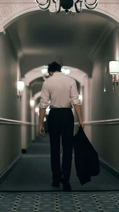 a man walking down a hallway with a suit case