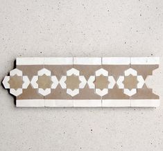 a white and brown tile border on a wall with geometric shapes in the middle,