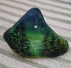 a green and black rock with trees painted on it