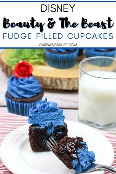 a chocolate cupcake with blue frosting is on a plate next to a glass of milk