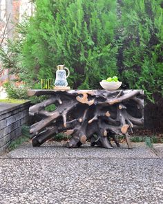 a table made out of driftwood in front of some trees