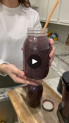 a woman holding a mason jar filled with purple liquid