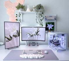 three computer monitors sitting next to each other on top of a white desk with flowers