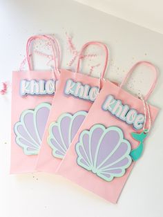 three pink bags with little mermaid designs on them