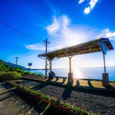 the sun shines brightly over an empty covered bench by the ocean on a sunny day