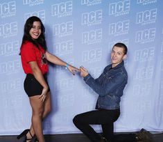 a man kneeling down next to a woman in front of a blue wall with the words ice on it