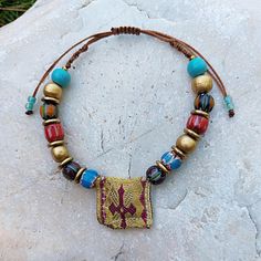 Discover the beauty and spiritual significance of this unique handmade Greek talisman amulet bracelet. Adorned with vibrant, multi-colored nepalese beads, wooden beads , bronze details and a distinctive fabric Greek amulet centerpiece, this bracelet combines traditional craftsmanship with a modern boho style. The adjustable cord ensures a comfortable fit for any wrist size. Perfect as a meaningful gift or a special addition to your own jewelry collection, this piece carries the essence of ethnic Handmade Multicolor Bracelets For Rituals, Bohemian Gold Beaded Bracelets For Meditation, Bohemian Bead Bracelet For Meditation, Spiritual Large Beads Bracelets For Festivals, Artisan Handmade Bracelets For Meditation, Multicolor Bracelets For Festivals, Spiritual Fair Trade Beaded Bracelets For Festival, Traditional Multicolor Beaded Bracelets Fair Trade, Spiritual Hand-wrapped Beaded Bracelets For Festivals