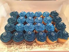 a box filled with blue frosted cupcakes on top of a table