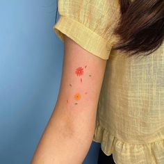 a woman's arm with an orange and red flower tattoo on the left side of her arm