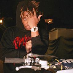 a young man with dreadlocks on his head sitting in front of a motorcycle