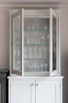 a white china cabinet with glass doors and shelves