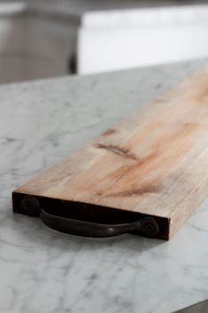 a wooden cutting board sitting on top of a white marble countertop next to a knife holder