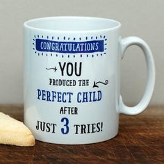 a white coffee mug sitting on top of a wooden table next to a piece of bread