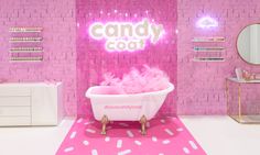 a bathroom with pink walls and a white bathtub in front of a neon sign that says candy cout