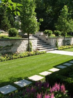 an outdoor garden with grass, flowers and stone steps leading up to the top of it