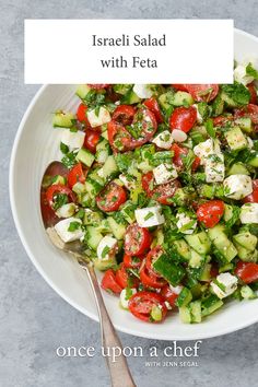 a white bowl filled with cucumber, tomatoes and feta cheese on top of a table