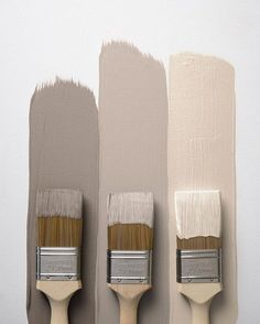 three paintbrushes with different shades of gray and beige on them, one is white