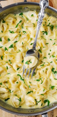 a pot filled with pasta and parsley on top of a wooden table