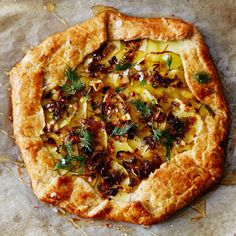 a pizza sitting on top of a table covered in cheese and toppings with herbs