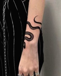 a woman's hand with a snake tattoo on it