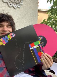 a young man holding up a pink and black record with the word love on it