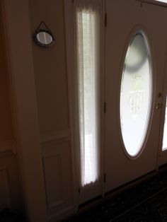 the sun shines through two oval windows onto a door with blinds on both sides