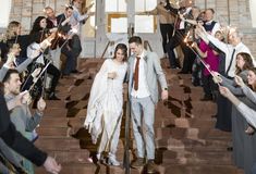 a bride and groom walk down the stairs with sparklers in their hands as guests look on