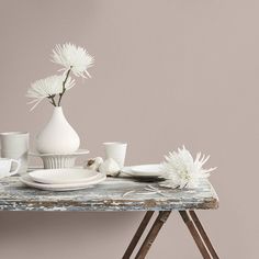 a table topped with white dishes and vases