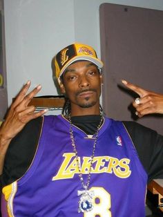 a man in a lakers jersey pointing to the side with his finger on one hand