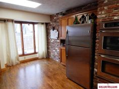 an empty kitchen with wood floors and brick walls