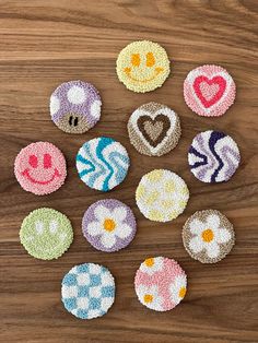 six handmade buttons with smiley faces on them sitting on top of a wooden table