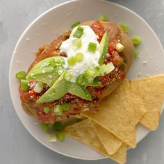 a white plate topped with a sandwich and tortilla chips next to a bowl of salsa