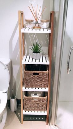 a white toilet sitting next to a wooden shelf with baskets on top of it in a bathroom