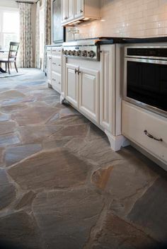 a kitchen with stone flooring and white cabinets