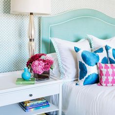 a white bed topped with lots of pillows next to a night stand filled with books