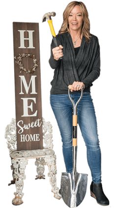 a woman standing next to a sign holding a hammer and a shovel in her hand