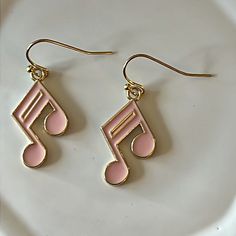 pink and gold musical note earrings on a white plate