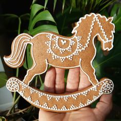 a hand holding a wooden rocking horse ornament