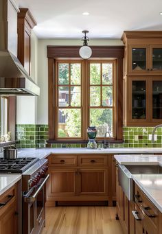 a kitchen with wooden cabinets and green tile on the wall, along with stainless steel appliances