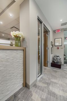 an empty office lobby with flowers on the counter and door to another room in the background