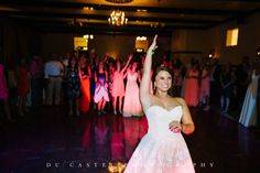 a woman in a white dress is dancing on the dance floor with her arms up