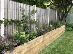 a garden with flowers and plants growing in the planter boxes next to a fence