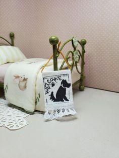 a small bed with a white and black dog on it's cover next to a doily