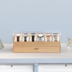 a set of six watches sitting on top of a wooden box next to two vases