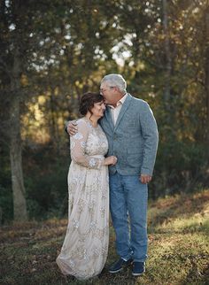 an older man and woman embracing in the woods