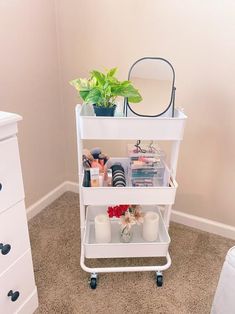 a white cart with some items on top of it in a room next to a dresser